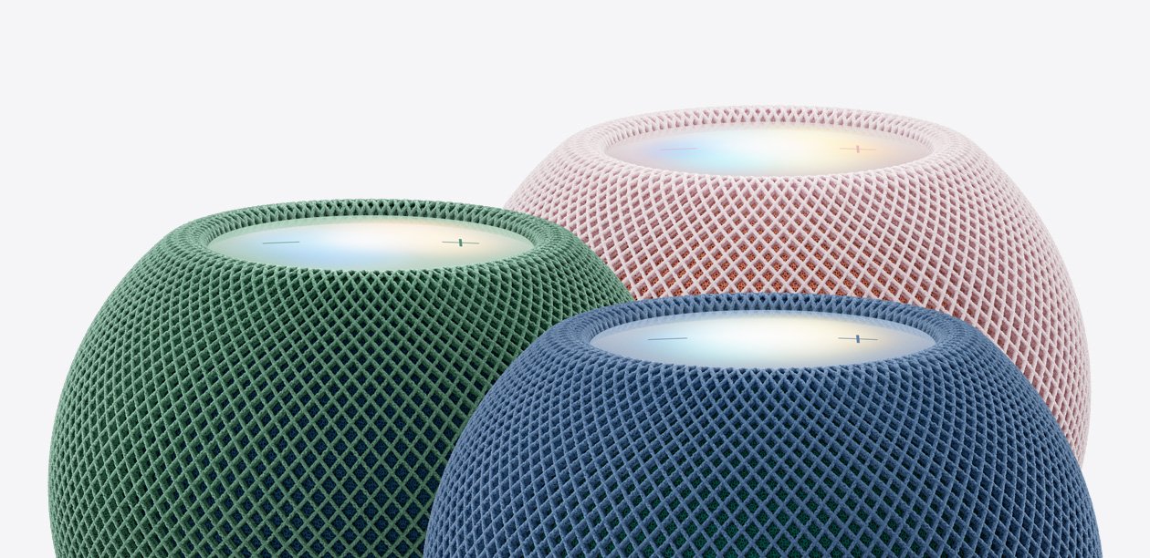 Primer plano de tres HomePod mini 2 en verde, azul y rosa, con sus superficies táctiles superiores iluminadas.