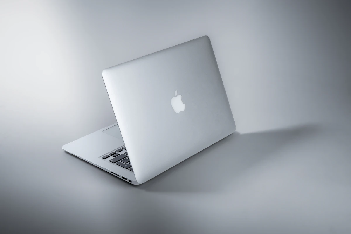 Un MacBook plateado abierto sobre una superficie gris, visto desde la parte trasera de la pantalla.